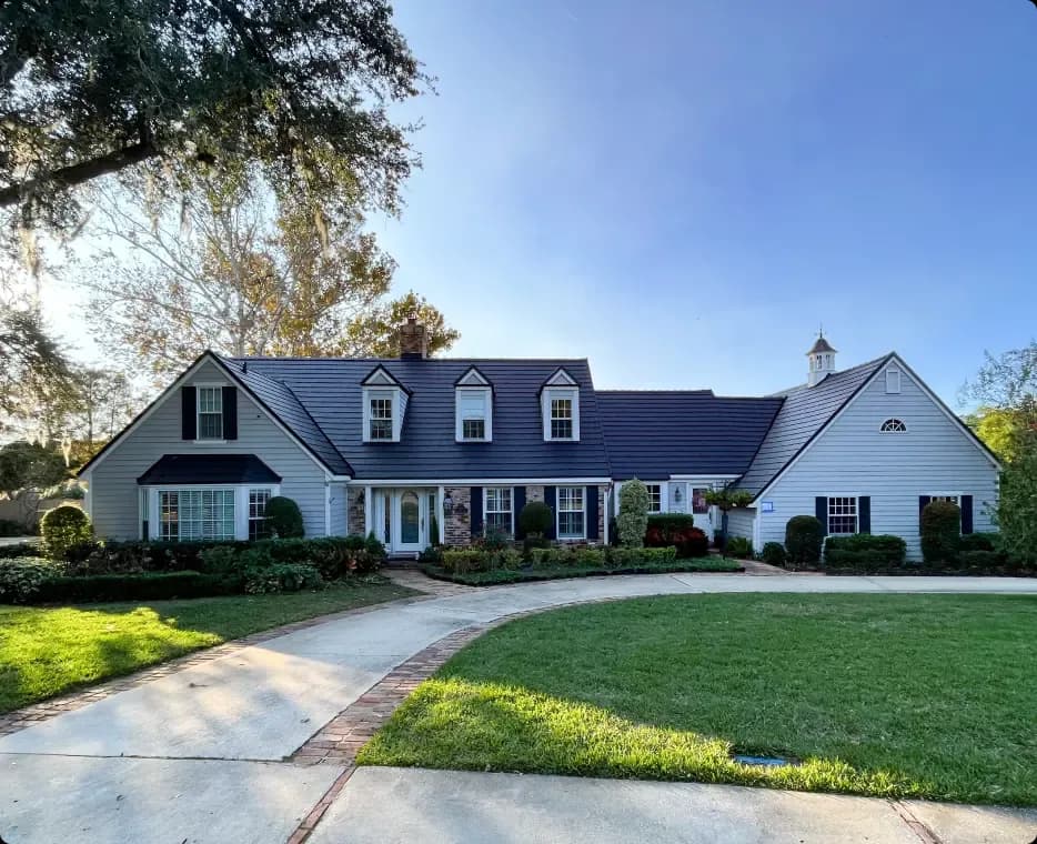 White two-story home with dormers and a dark Metlok metal roof