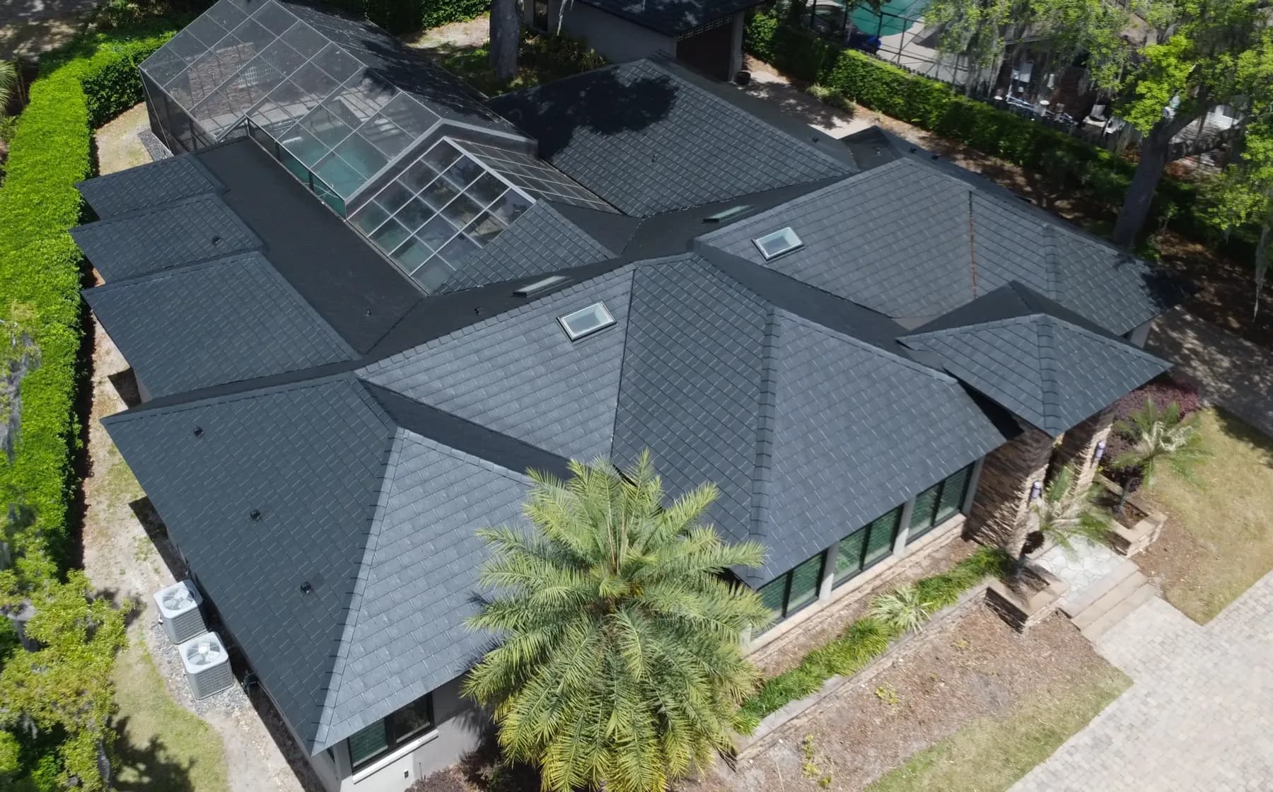 Aerial view of a home with a Black Summit Metlok roof among palm trees