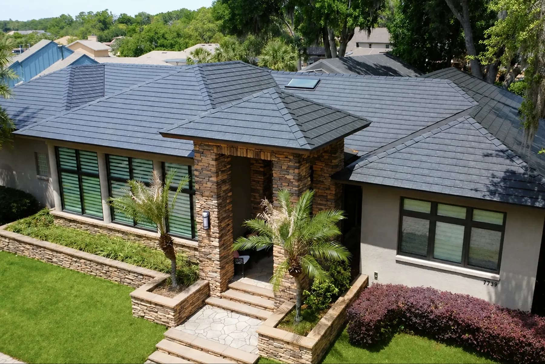 Stone-front ranch home with a dark Metlok metal roof